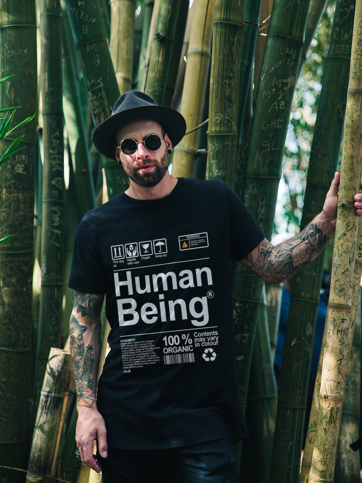 Man wearing a black t-shirt with 'Human Being' text in a bamboo forest